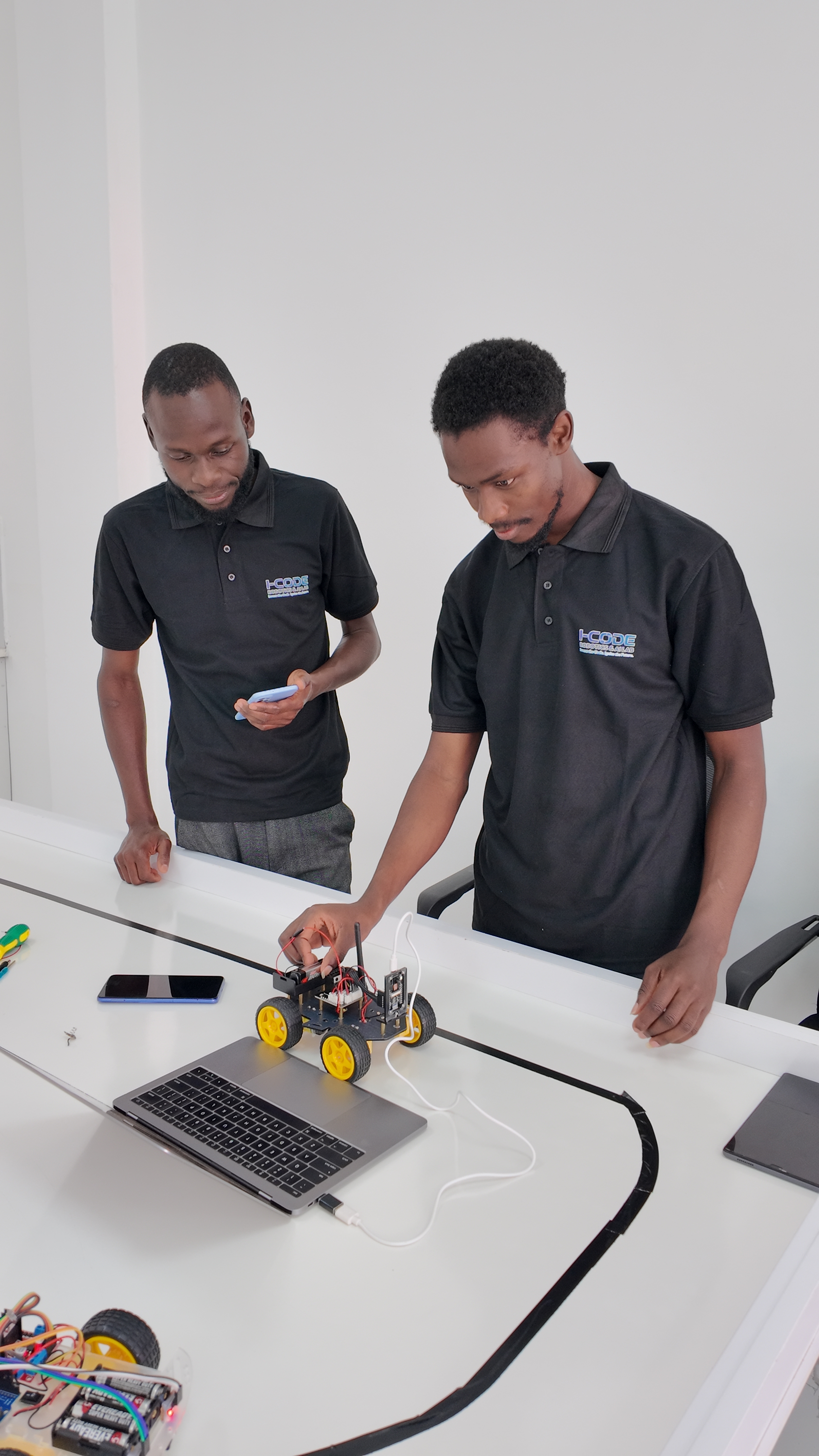 i-CODE instructors testing and programming Arduino robot car