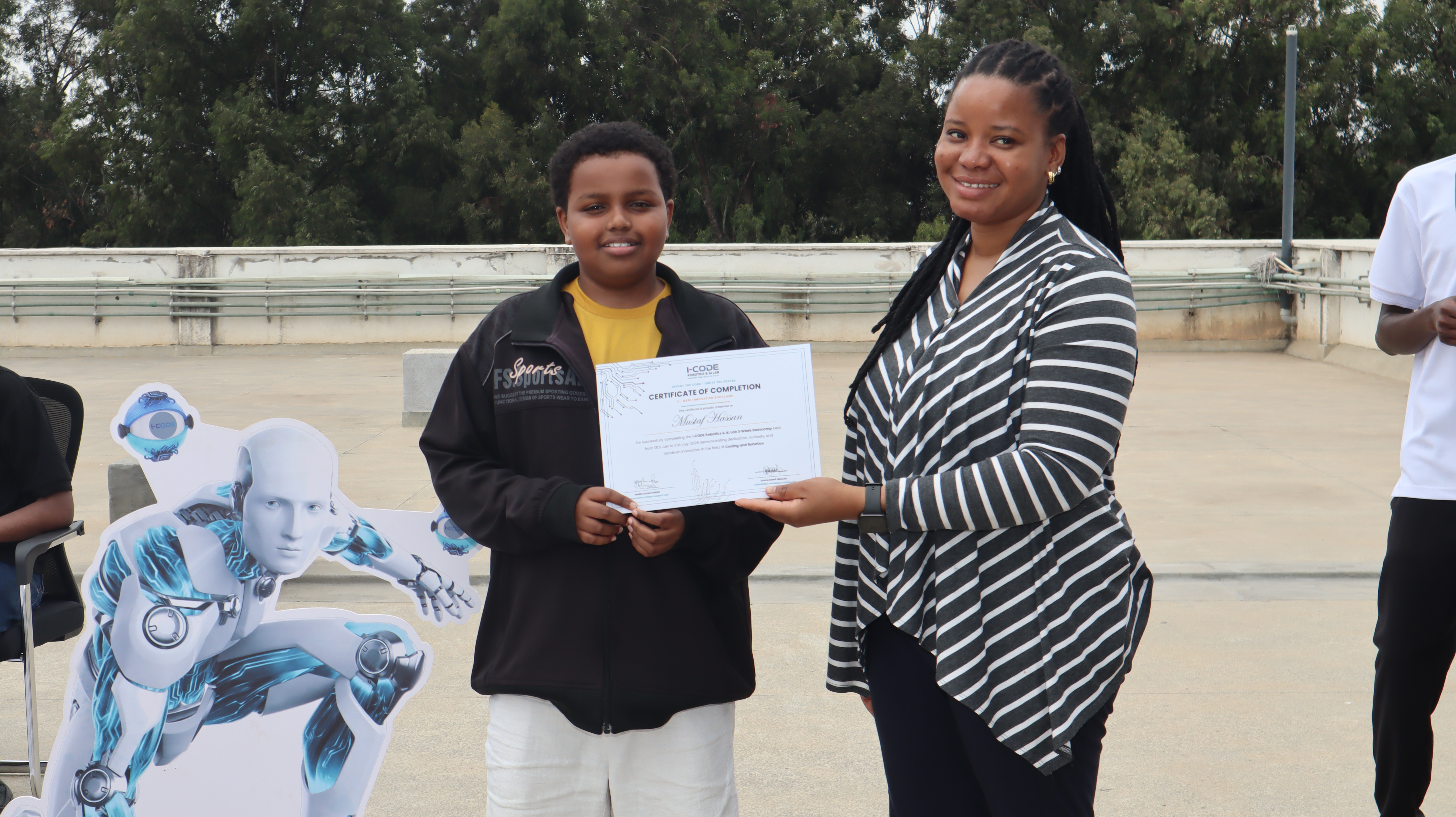 Young student proudly holds i-CODE Certificate of Completion